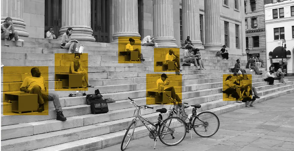 Two bicycles parked at the bottom of a set of marble steps where people are seated