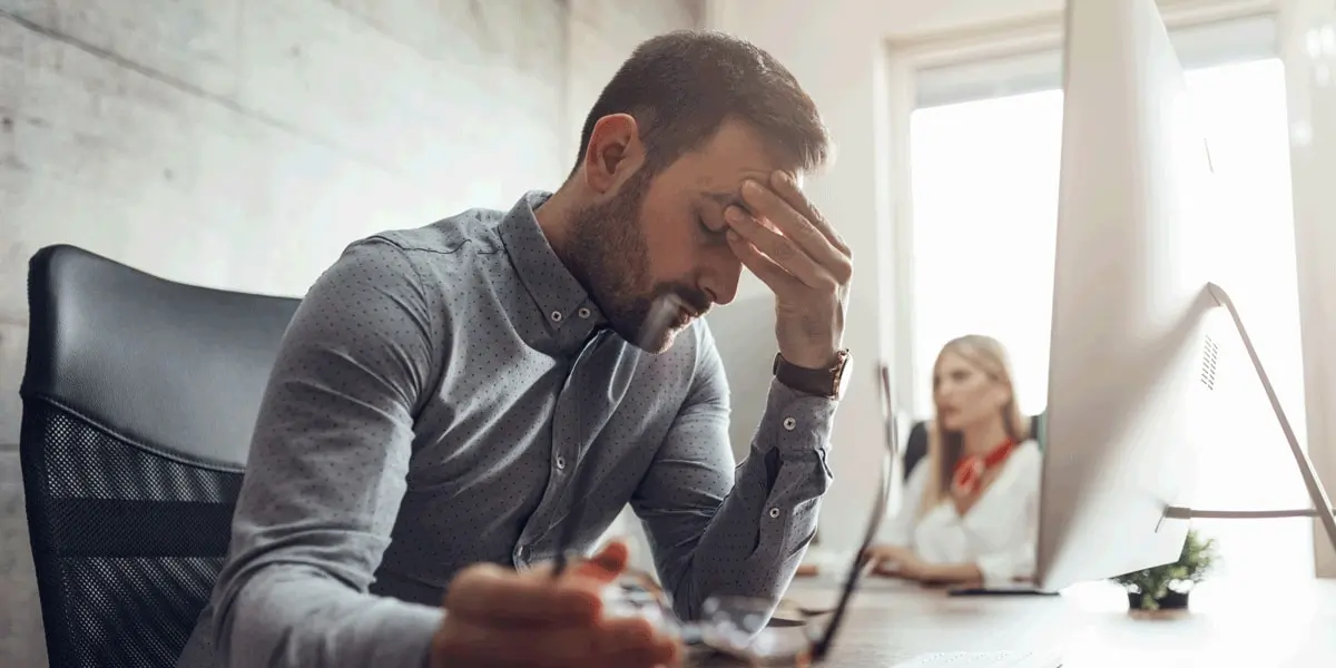 UX designer sitting at a desk resting their head on their hand