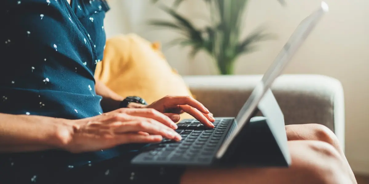 A UX writer sitting on a couch, with a tablet in their lap, writing a product page