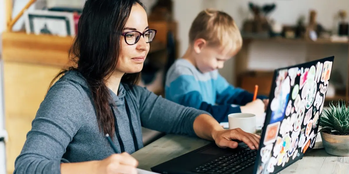 A new UX writer at home, working on her UX writing course as her child plays nearby