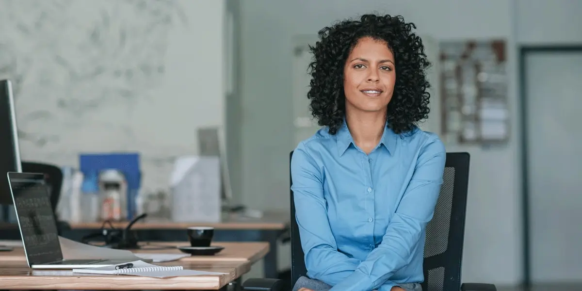 A UX designer sitting at her desk with her UX design portfolio examples, smiling at the camera