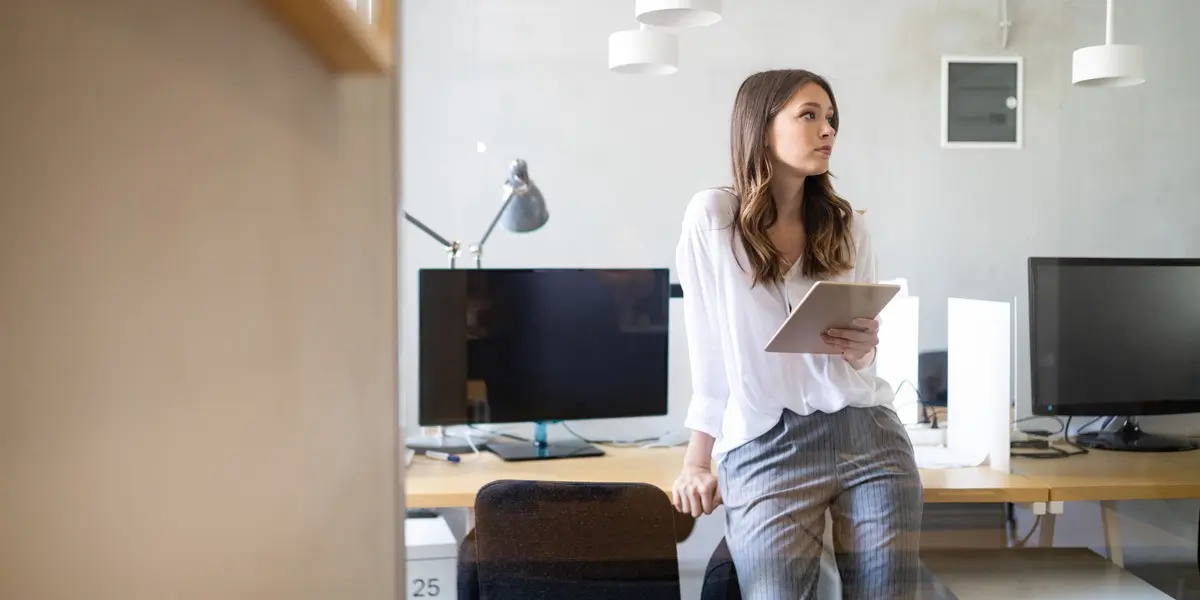 A data analyst leaning on a desk in an office