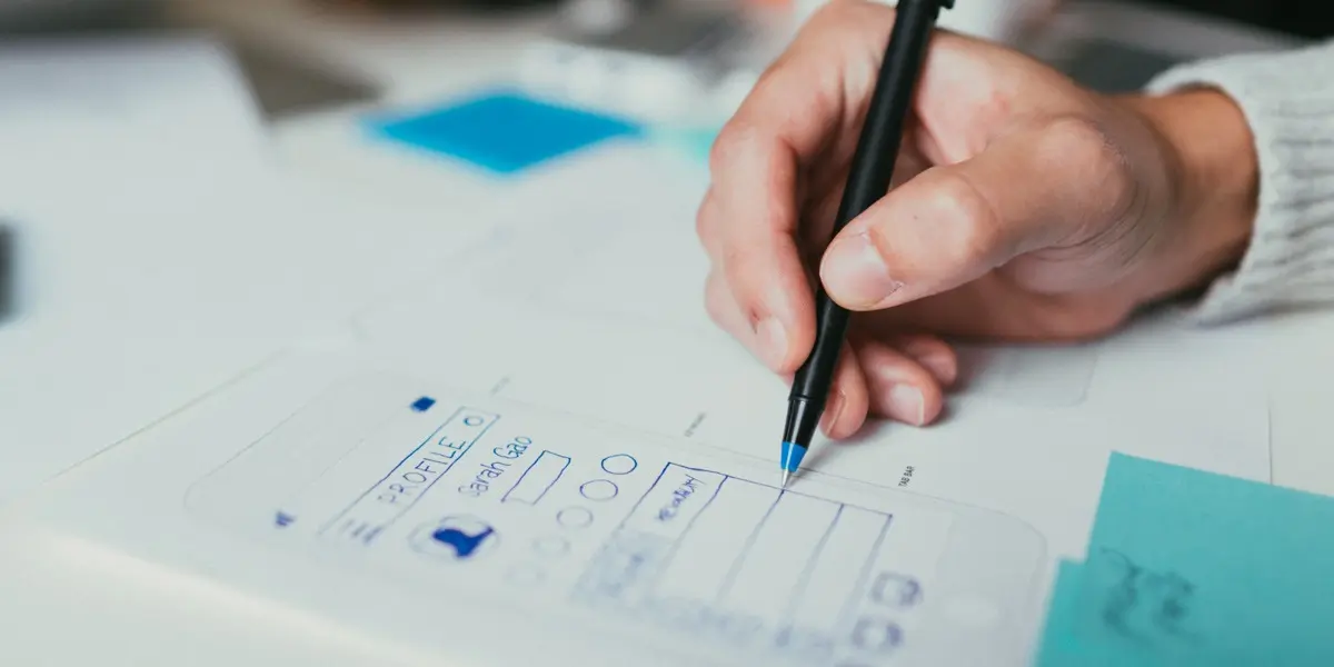 Close-up of a designer's hand working on paper prototypes