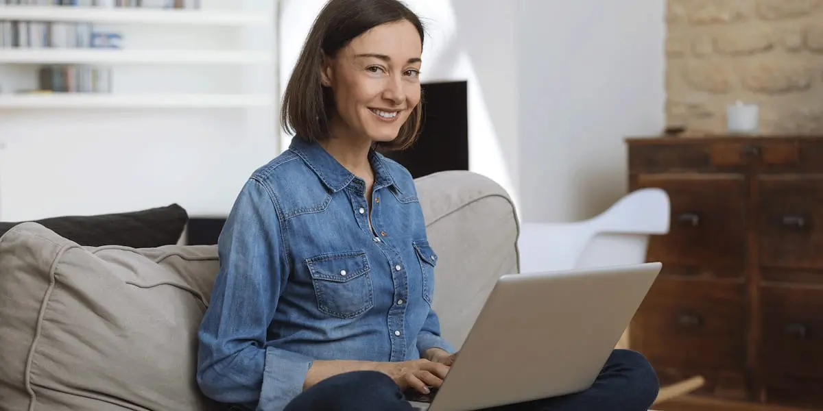 A UX researcher sitting on a couch, working on a laptop