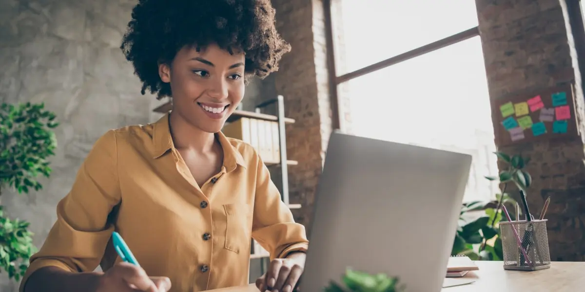 A data analyst smiling, looking at a computer screen