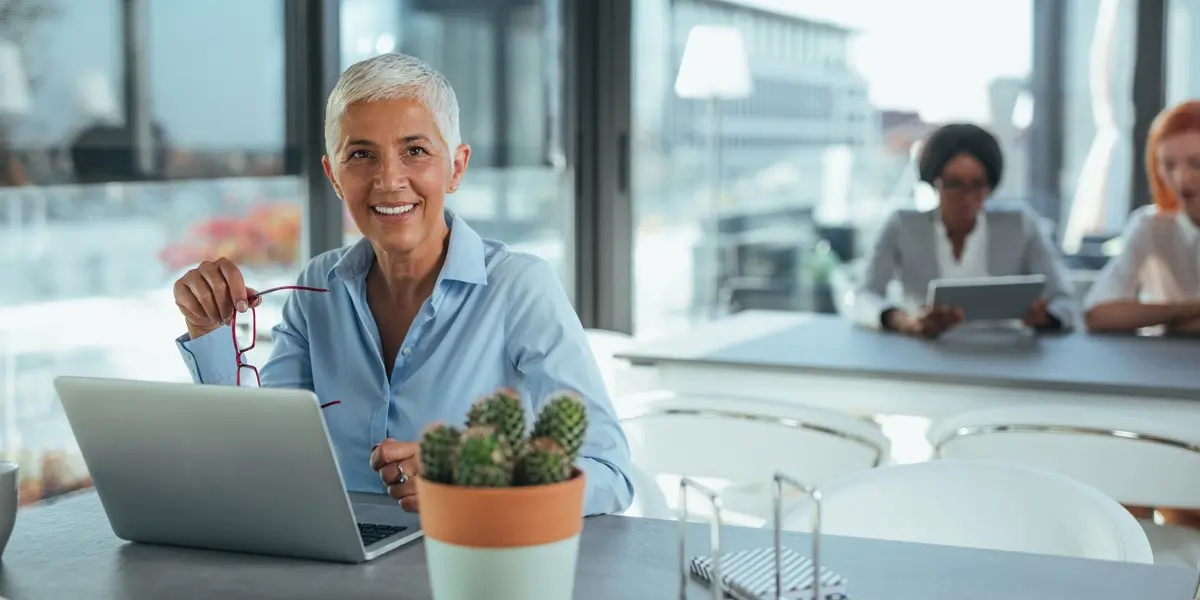 A data analyst sitting at a desk with a laptop, smiling