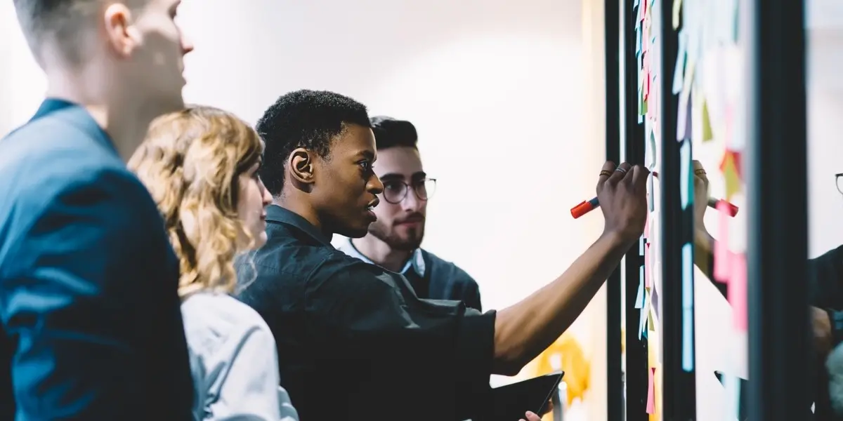 A group of UX professionals gathered around a whiteboard, planning inclusive UX research