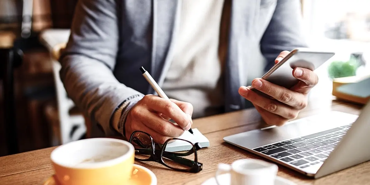 A UX writer working at a cafe with a laptop and note pad