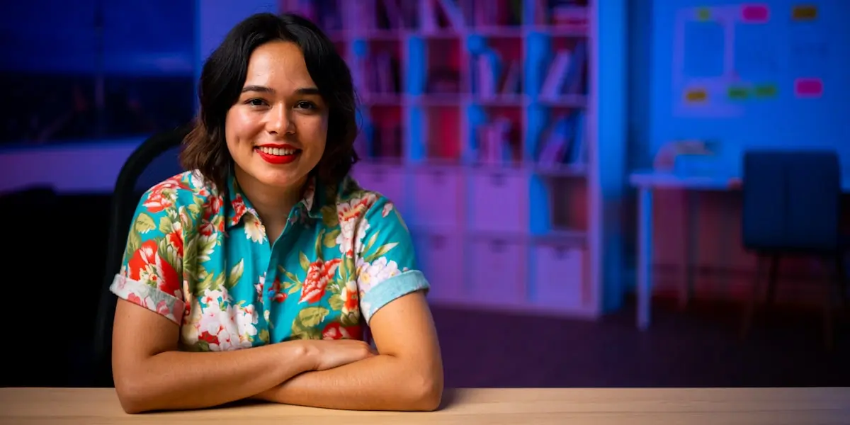 UX design graduate Maureen sitting at a table in an office