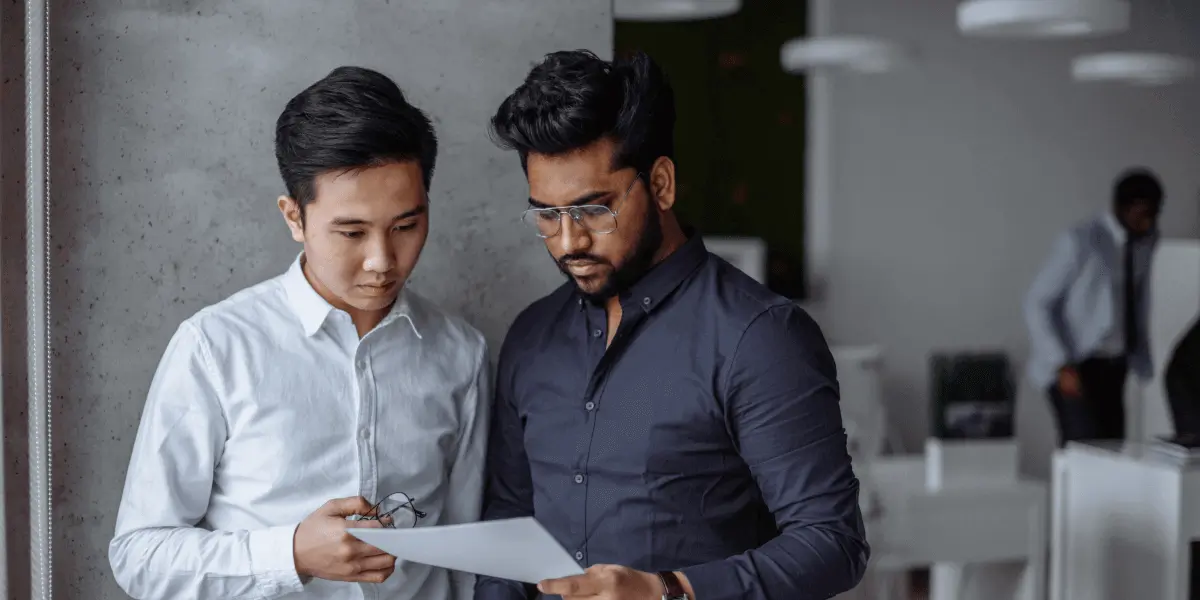 Two financial data scientists standing side by side, looking at a document