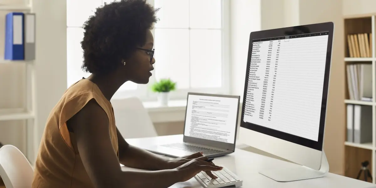 A data analyst in side profile, looking at an Excel spreadsheet on a computer