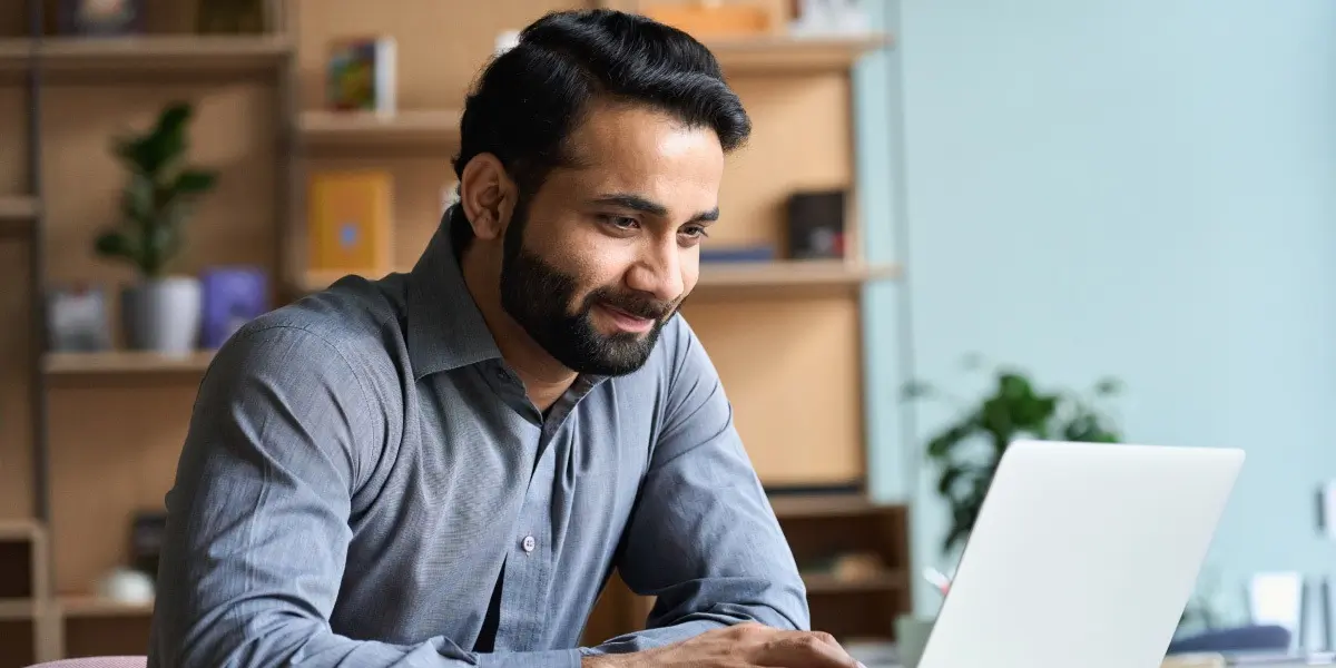 A data analyst in side profile, looking at a laptop screen