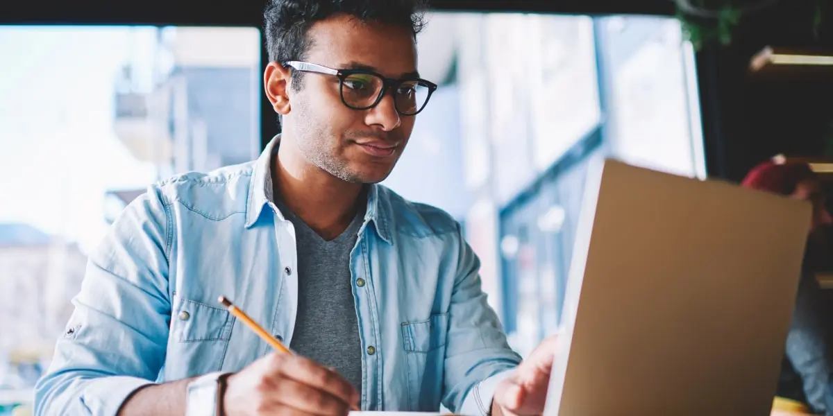 An aspiring designer sitting at a desk, working on a laptop, researching how to become a UI designer in 2023