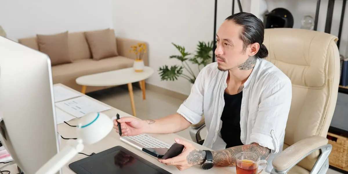 A UX designer sitting at a desk, working on a large desktop computer