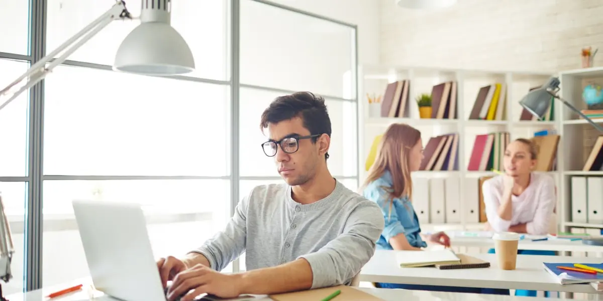 A business analyst sitting at a desk, working on a laptop