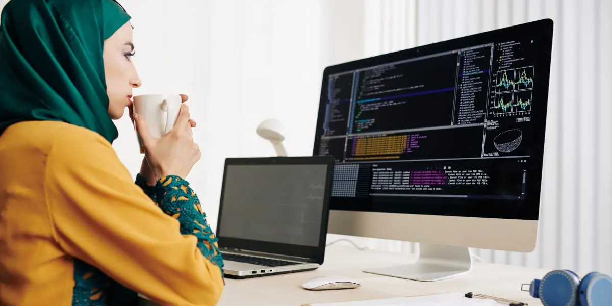 A data analyst in side profile, looking at code on a computer screen