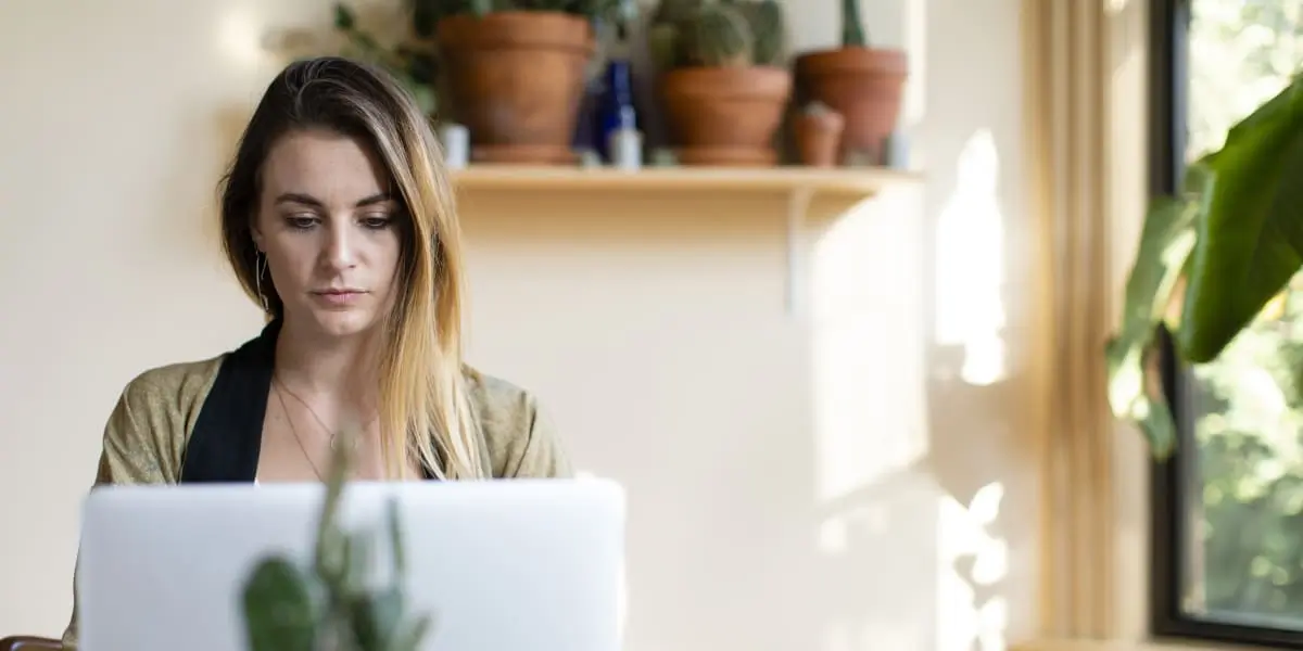 A career changer sitting in plant-filled room with a laptop