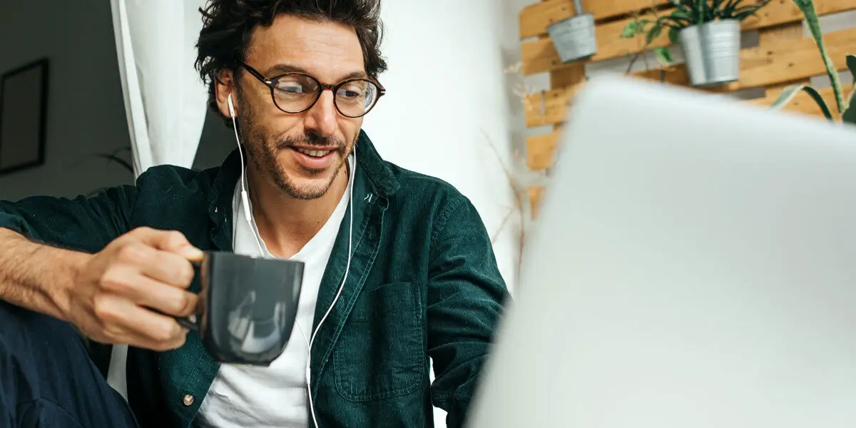 A python developer working at a computer, holding a mug of coffee