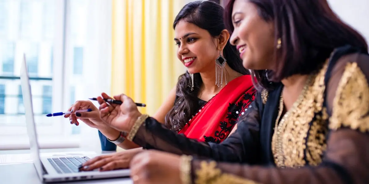 Two business analysts in side profile, looking at a computer