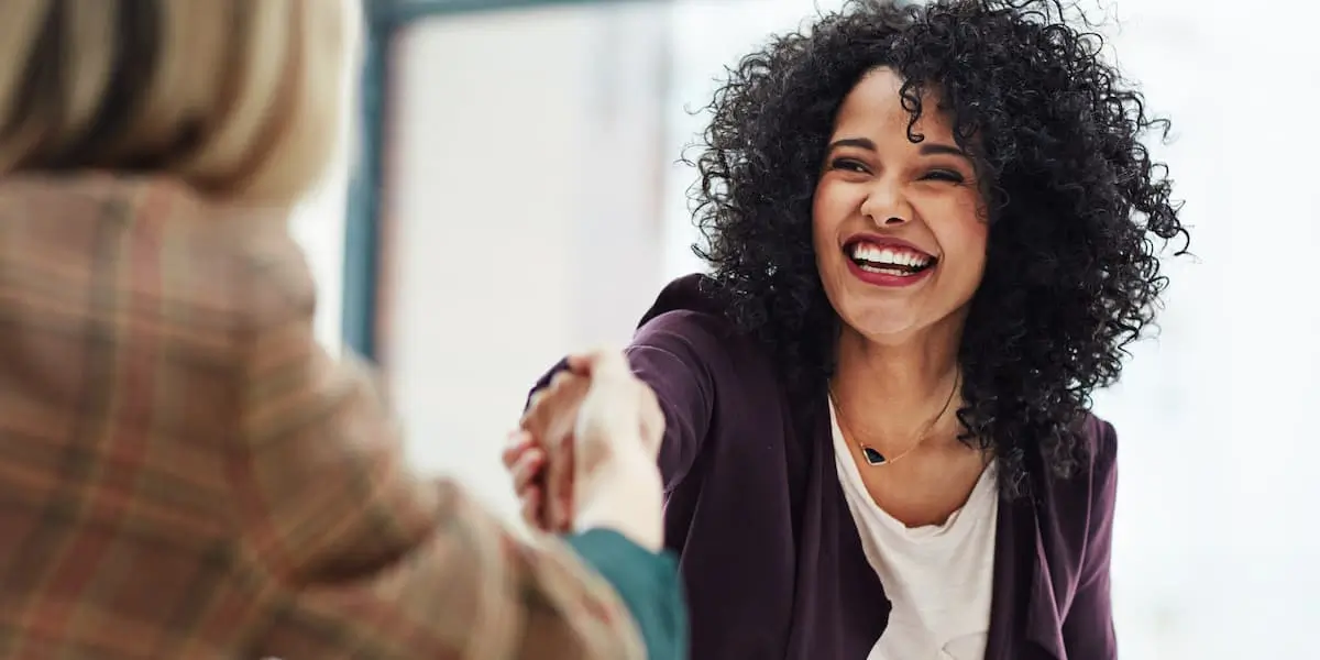 a designer at a ux job interview smiles while shaking the interviewer's hand