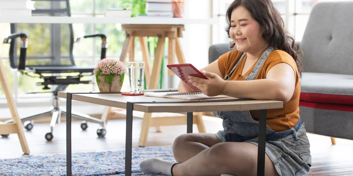 A person sitting on a rug, holding an iPad, learning about omnichannel marketing