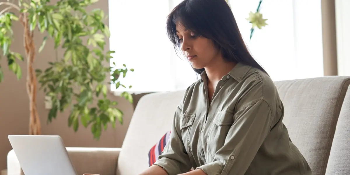 An aspiring marketer sitting on a sofa, researching how to become a social media manager