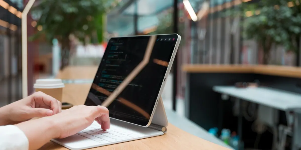 Hands writing Python 3.8 code on a laptop on a table with a coffee cup.