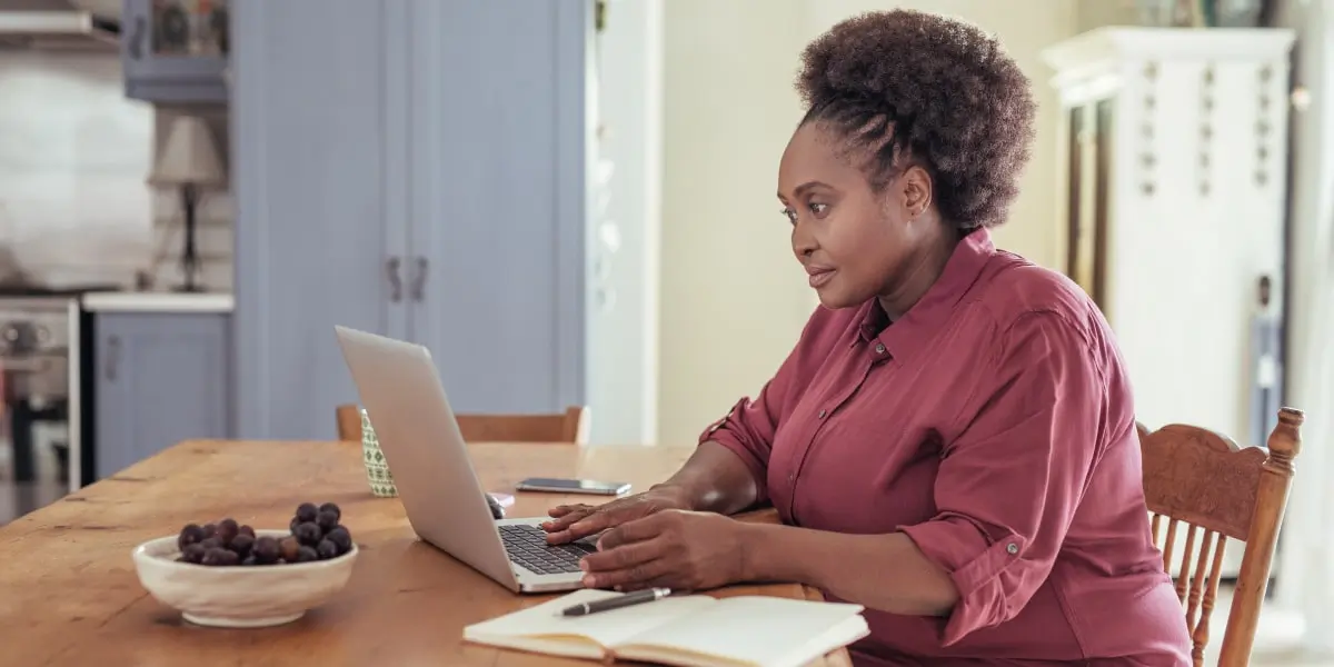 An SEO specialist sitting at a table, working on a laptop