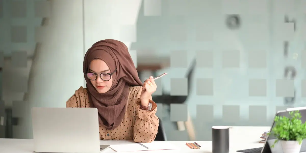 A UX designer sitting at a desk, working on a laptop, writing a problem statement for a product redesign project