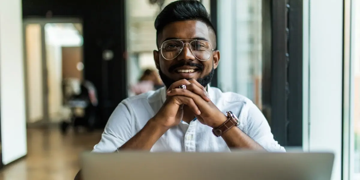 A digital marketer smiling, working on a laptop