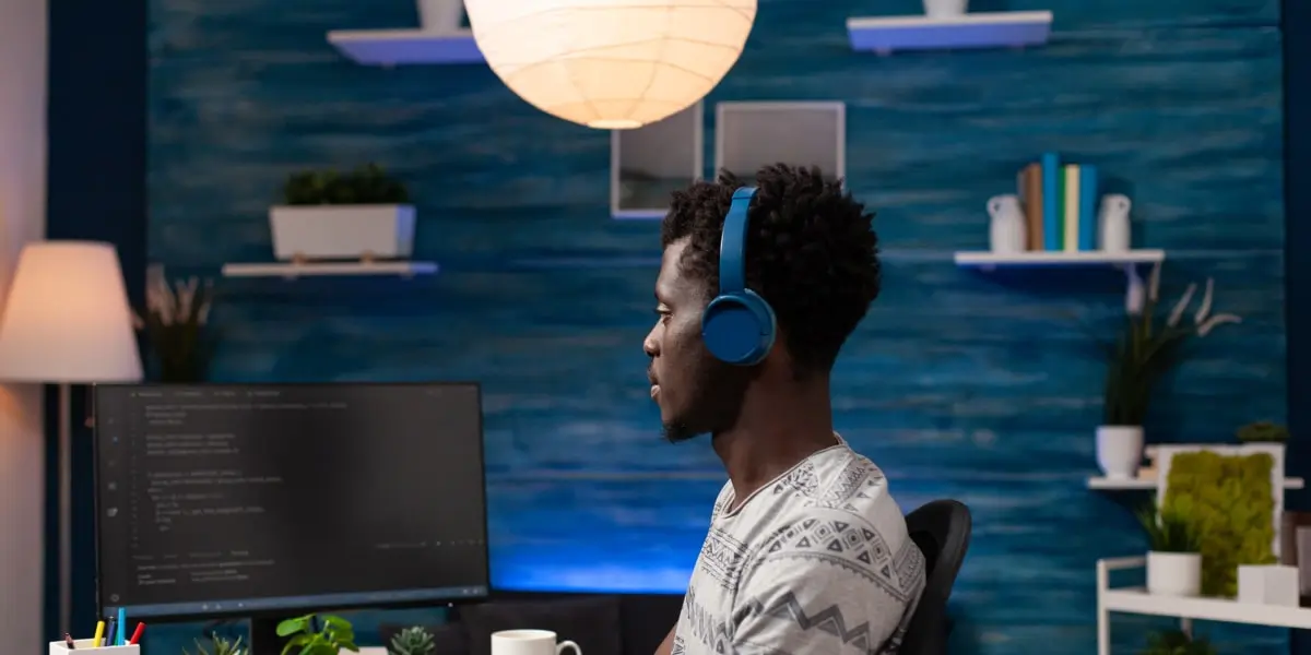 A JavaScript developer using the React.js library sits at his desk with a mug of coffee in a home office.