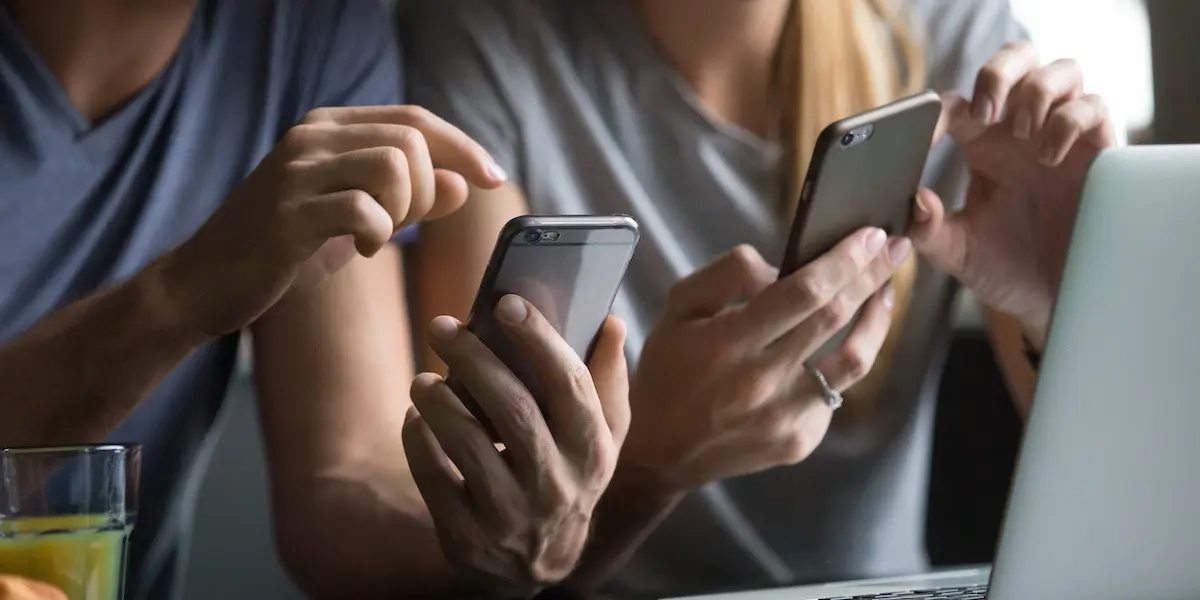 Close up of two people using social media platforms on their smart devices.