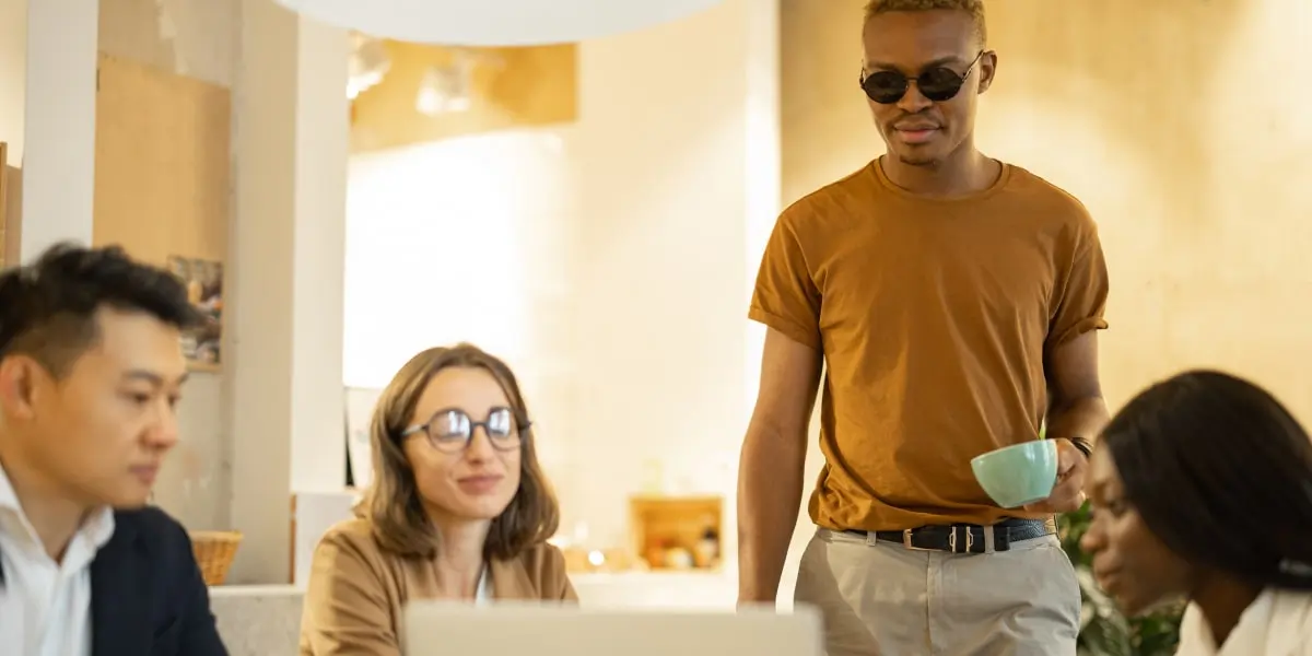 A vision-impaired product manager sits in a staff cafe with their team.