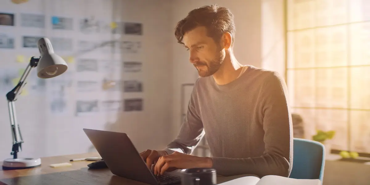 Digital marketing specialist works in his home office in the late afternoon