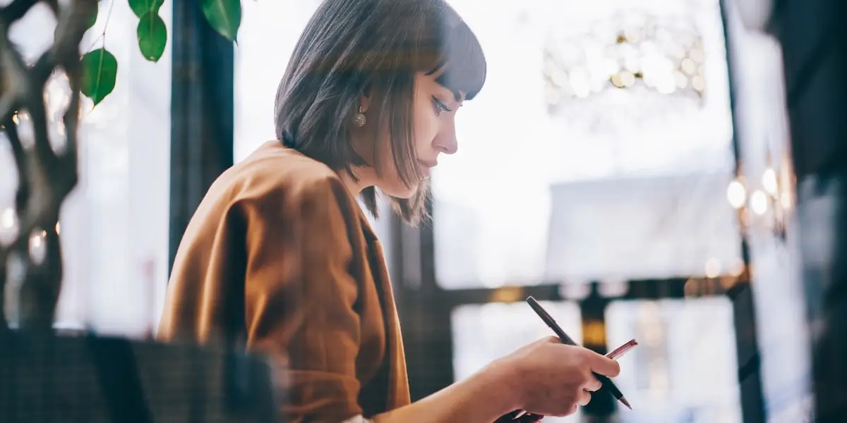 Woman using social media on her phone, learning how to become a social media manager with no experience