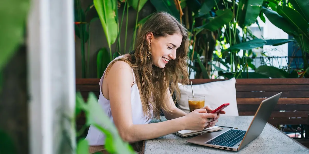 A woman sits in a cafe at a laptop researching product manager job descriptions.