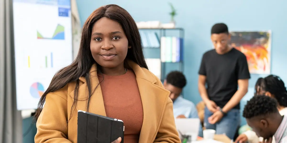 A product manager who works in a recession-proof industry holding a tablet at a meeting.