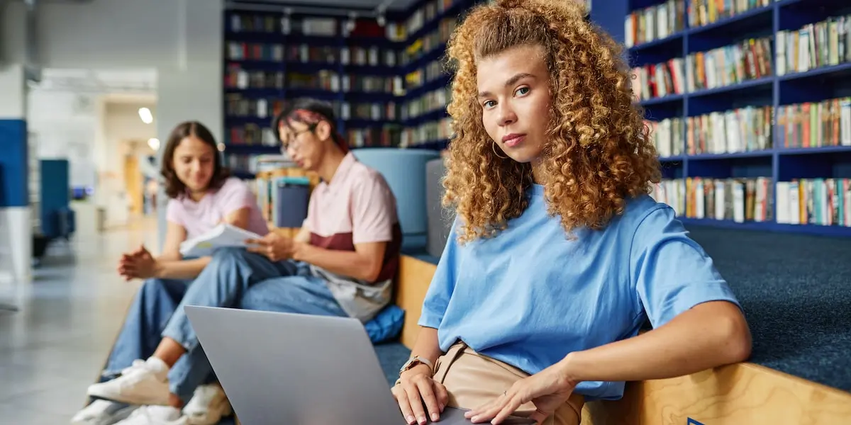 A cloud engineer sits in a start-up office with her laptop staring at the camera.