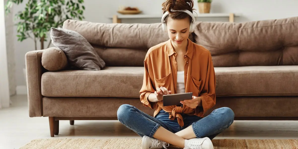 Woman sitting on floor creating her social media portfolio from her tablet.