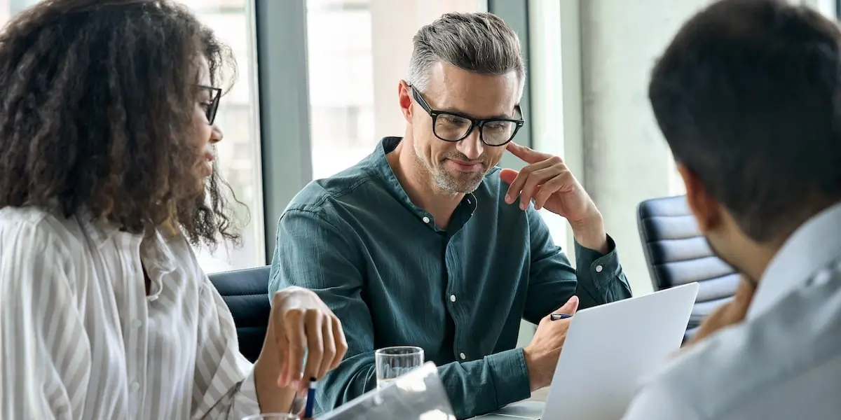 Group of three people sitting around a laptop, answering SQL interview questions