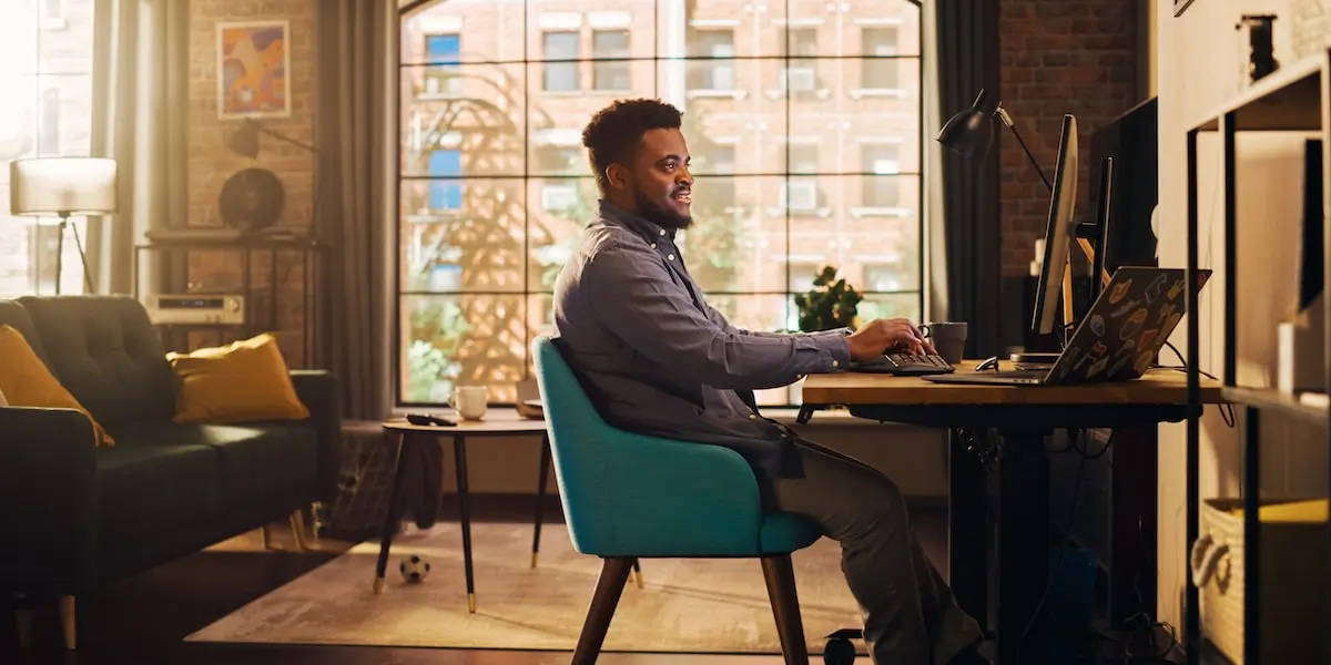 A software developer sits in his airy home office working at a computer.