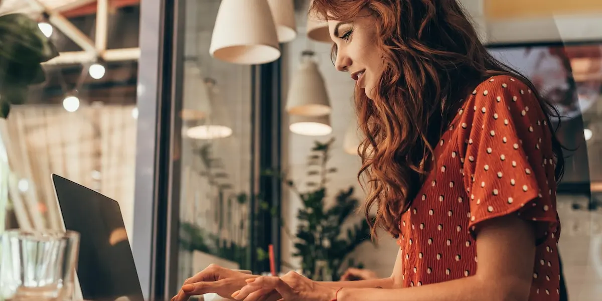 A woman takes an online product management training course on her laptop in a cafe.