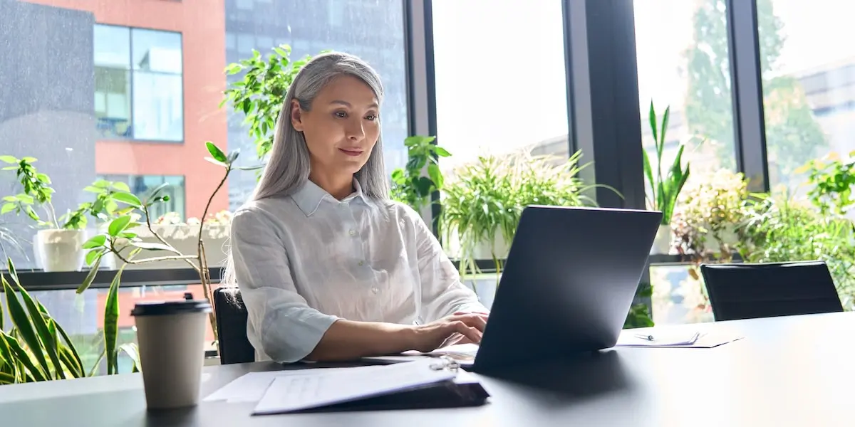 A MEAN stack developer sits in her bright office typing at her computer.