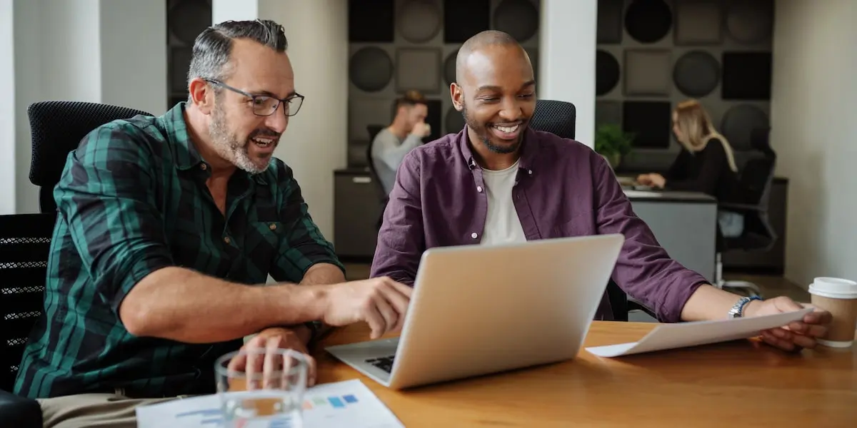 Two product managers sit in an office at a laptop discovering what is scrum.