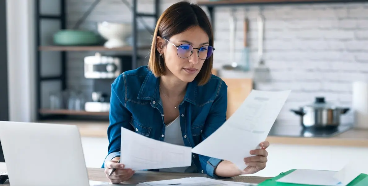 A woman looks over her software engineer cover letter and resume at her kitchen counter.