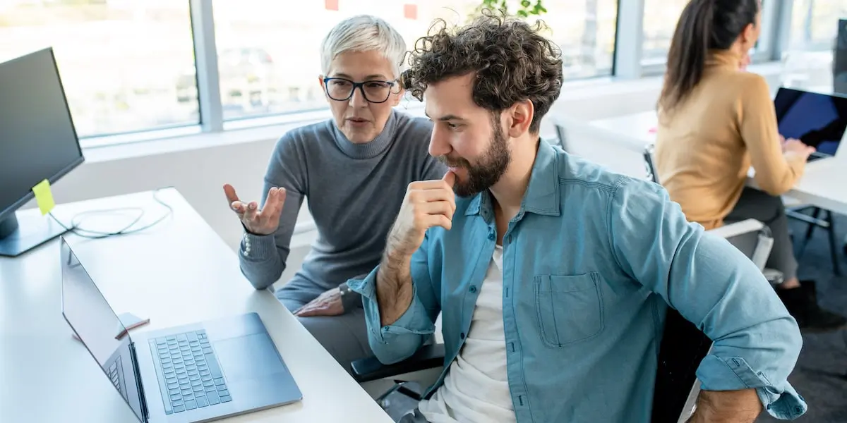 A mentor shares scrum master responsibilities with her product mentee in an office.