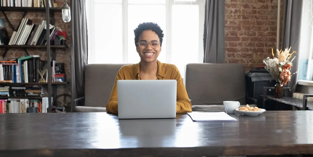 A woman sits at a laptop at home planning her software engineer career path.