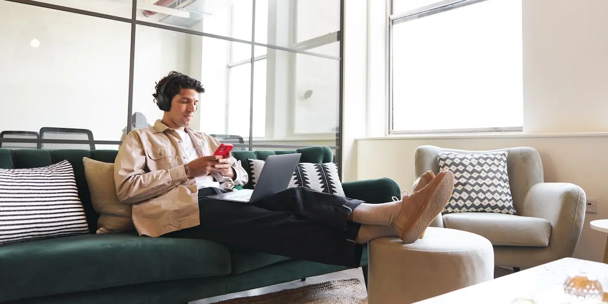 A product manager works on a user story on his laptop in a bright office.