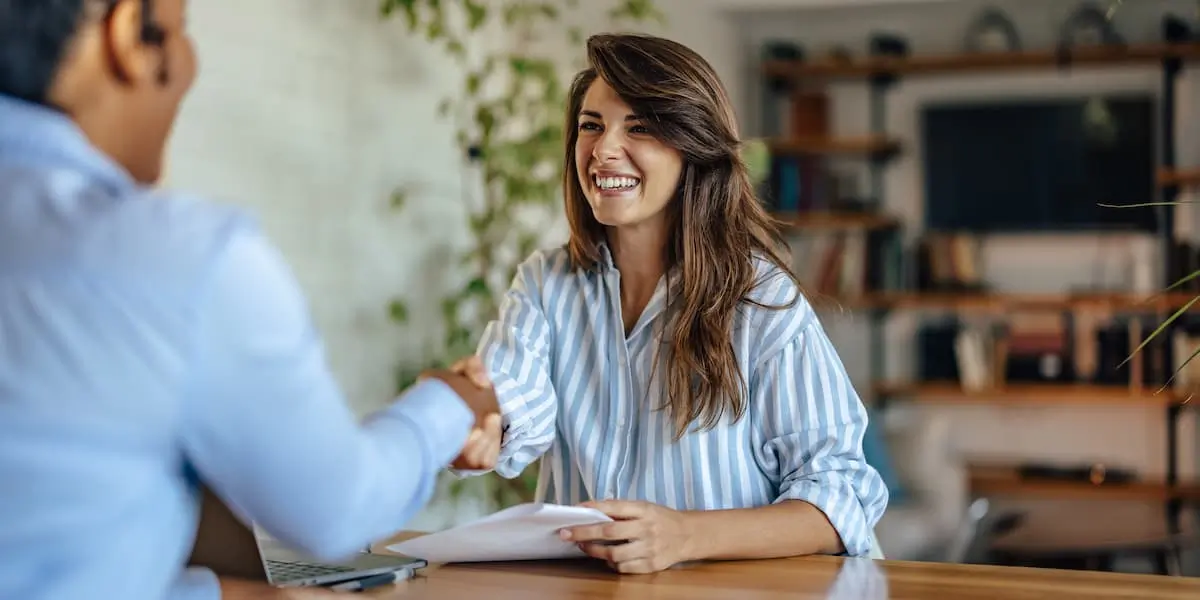 A succesful job interview candidate shakes hands with the interviewer after answering job interview questions