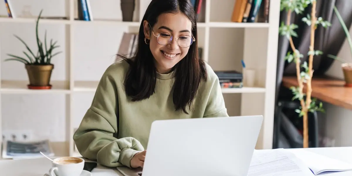 a young woman at her laptop looking excited after finding a new job